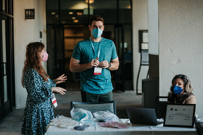 Three masked volunteers chatting and preparing for attendees